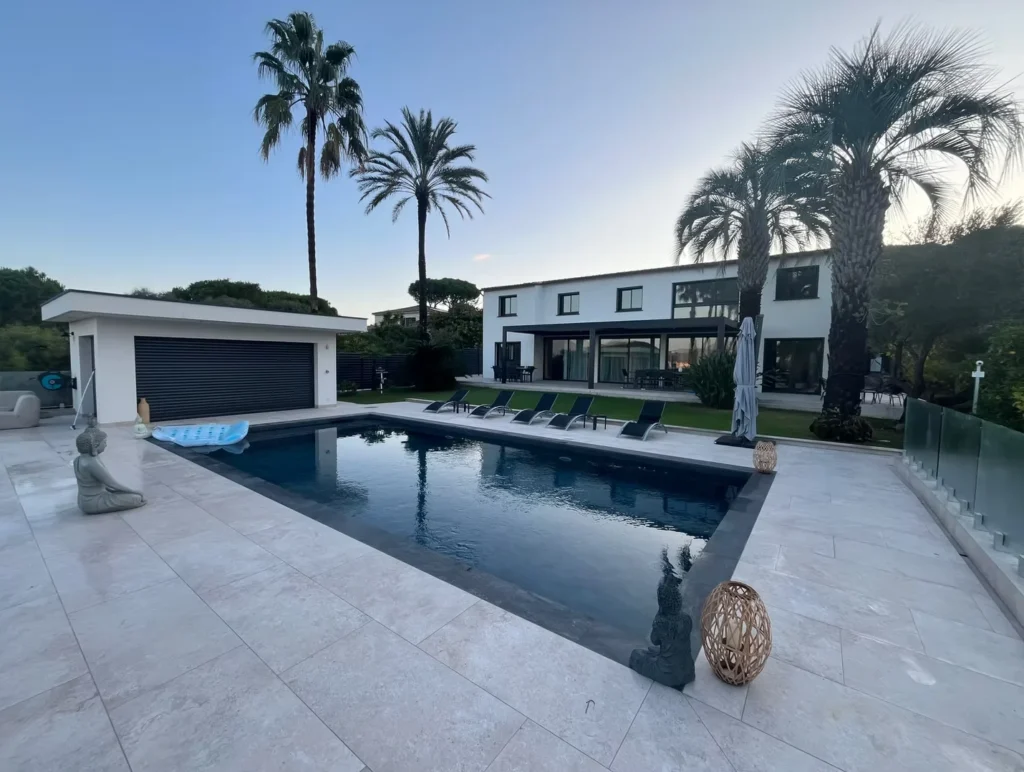 Piscine et pool house dans un jardin avec palmiers
