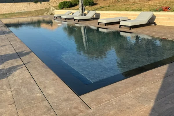 Piscine sur mesure à débordement et plage en grès cérame
